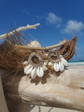 Decorative earrings with seashells on a wooden log with a beach background