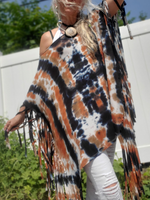 Person wearing a tie-dye poncho with extra long fringes outdoors