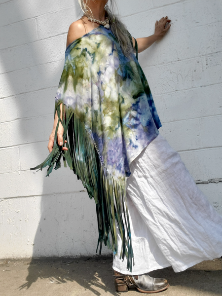 Person wearing a colorful fringe garment against a white wall