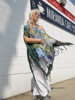 Woman wearing a colorful shawl in front of a building with a sign for Miranda Cafe.