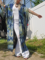 Person wearing a blue and green tie-dye kimono over a white outfit outdoors.