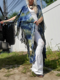 Person wearing a blue tie-dye kimono with fringes in an outdoor setting