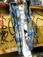 Person holding a blue and green patterned scarf in front of a graffiti-covered wall.