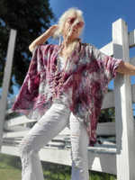 Woman wearing a pink and white patterned top and white pants standing outdoors.