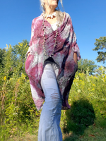 Person wearing a flowing pink and purple garment in a natural setting with trees and blue sky.