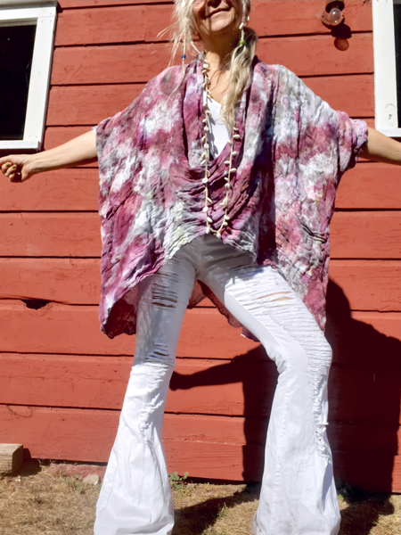 Person wearing a pink floral kimono over a white top and pants, standing in front of a red wooden wall.