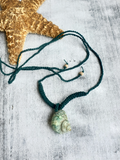 dark green cord Necklace with a green turbo shell pendant on a textured surface
