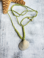 Lime green crocheted cord necklace with a sgrey hell pendant on a textured surface