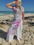 Woman in a tie-dye dress standing on a beach with ocean in the background