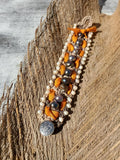 Bracelet with orange and gray beads on a wooden surface