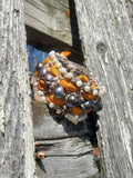 Decorative wreath with orange and silver elements attached to a wooden surface