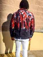 Person wearing a tie-dye jacket standing against a wall. A back shot