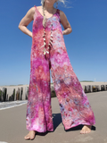Person wearing a colorful tie-dye jumpsuit on a beach.