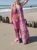 Person wearing a colorful tie-dye jumpsuit on a beach