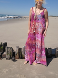 Woman in a colorful dress standing on a beach with wooden posts and ocean in the background