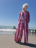 Person wearing a colorful outfit on a beach with clear blue sky and ocean.
