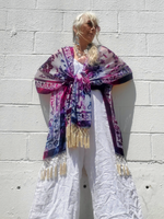 Person wearing a kimono with fringe against a white brick wall
