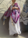 Person wearing a purple-pink kimono over a white linen jumpsuit against a graffiti-covered wall.