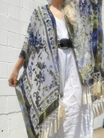 Person wearing a floral kimono with tassels against a white wall