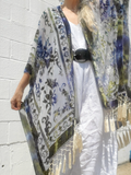 Person wearing a floral kimono with tassels against a white wall