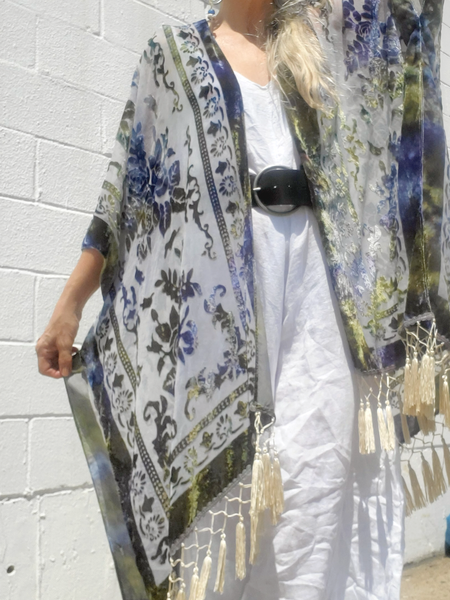 Person wearing a floral kimono with tassels against a white wall