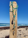 Beaded necklace with shells hanging on a wooden post on a beach