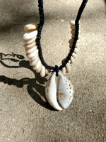 Necklace with shell pendant on a sandy surface