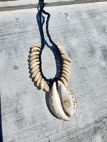 Shell necklace with a leather cord on a textured surface