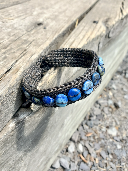 beaded  woven leather Bracelet with lapis lazuli stones on a wooden surface