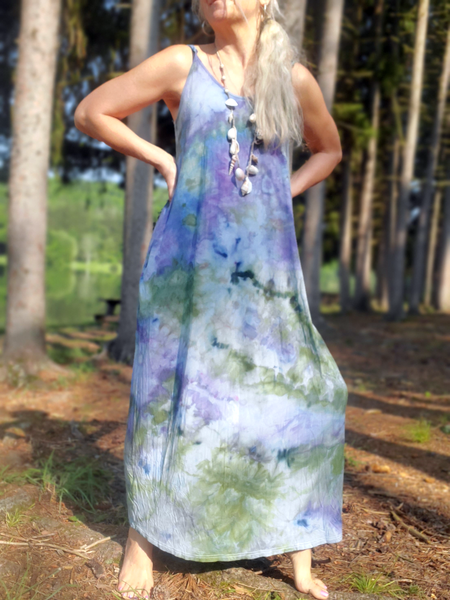Woman wearing a long, floral-patterned dress standing outdoors with trees in the background