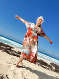 Woman in a colorful dress standing on a beach with clear blue sky
