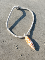 Necklace with a shell pendant on sandy ground