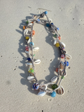 Necklace with colorful beads and shells on a sandy surface