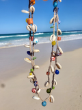 Colorful beaded necklace on a sandy beach with ocean view