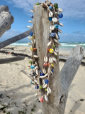 Decorative necklaces made of shells and beads on a beach with ocean view