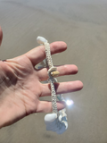 Hand holding a necklace with a blurred beach background