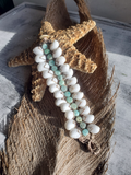 Beaded bracelet with white and turquoise beads on a textured surface