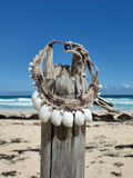 Necklace with white shells and natural cord on a wooden post by the beach