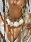 Close-up of a person wearing a large  moon shells choker with a blurred natural background