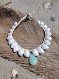 Necklace with white  shells and an aqua stone on a sandy background