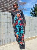 Person wearing tie-dye overalls standing against a tiled wall.
