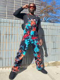 Person wearing colorful tie-dye overalls standing against a tiled wall.
