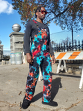 Person wearing colorful tie-dye overalls standing outdoors with a clear sky.
