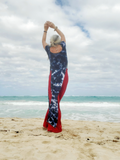 Person wearing a tie-dye outfit on a beach with ocean and sky in the background