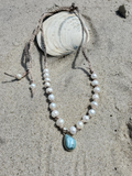 Pearl necklace with a larimar pendant on sand