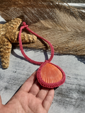Shell pendant with pink rope on a wooden surface