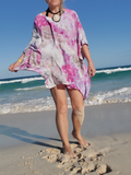 Person wearing a colorful dress on a beach with ocean waves in the background