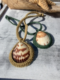 Two shell necklaces with green and brown cord on a wooden surface.