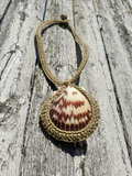 Seashell pendant with braided cord on a wooden surface