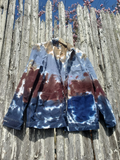 Tie-dye jacket on a wooden surface with a wooden fence and blue sky in the background
